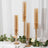 Elegant amber glass candle holders on a table with greenery and wine glasses.