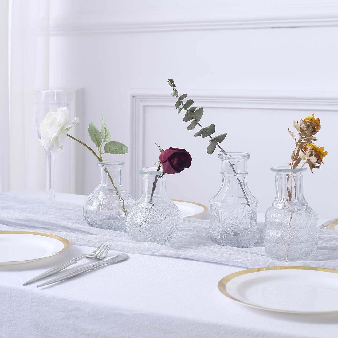 Glass vases with flowers on a dining table setting