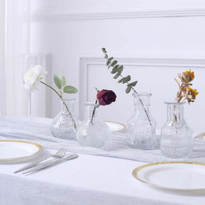 Glass vases with flowers on a dining table setting