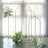 Gold floral arch stands with white and yellow flowers in a bright room.