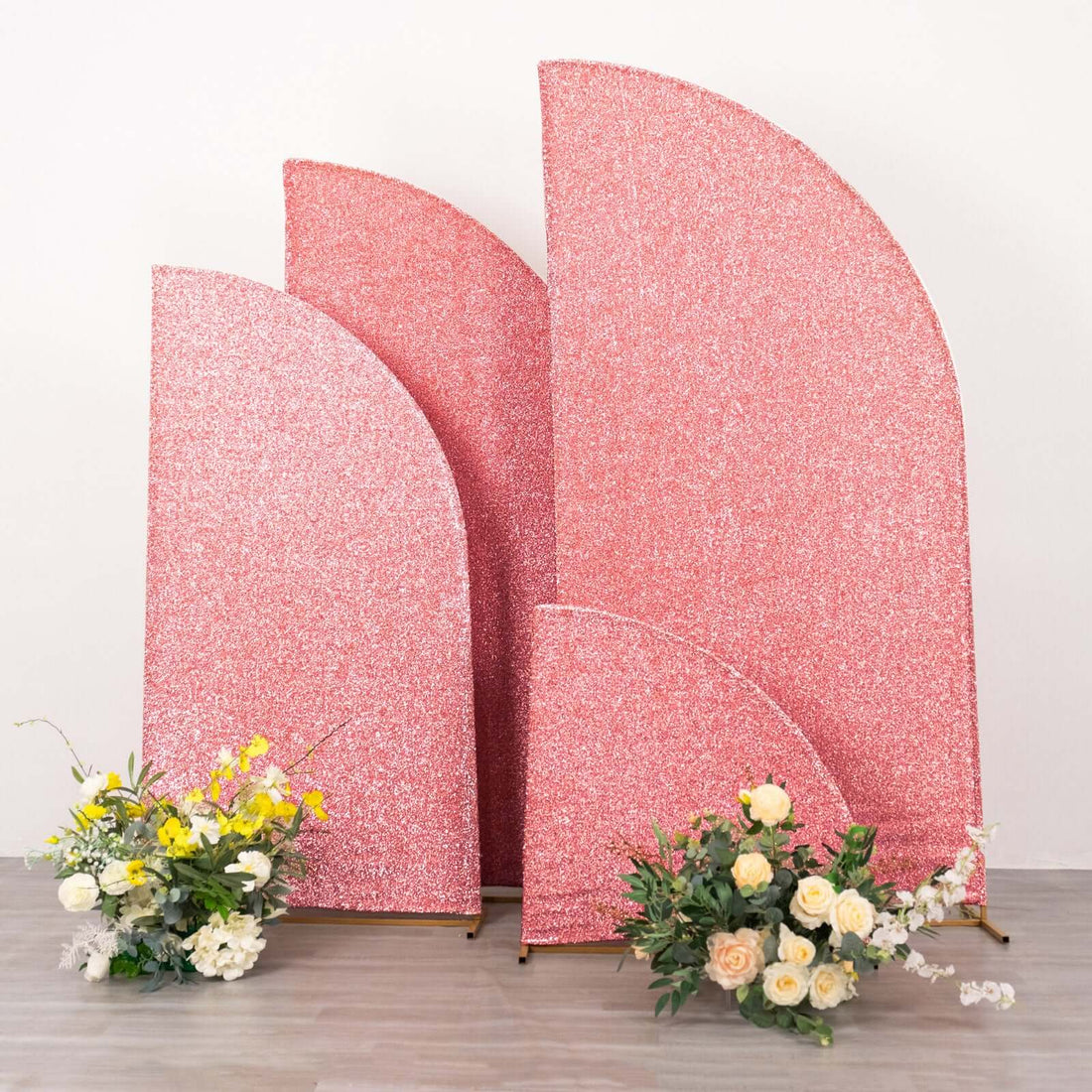 Glittery pink backdrops with floral arrangements in front of them.