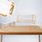 Geometric display stands with white surfaces and gold frames on a wooden table.