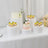 Decorative cakes and cupcakes on white pedestals at an event setup.