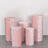 Set of five pink velvet pedestals in varying heights on a gray surface.