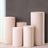 Set of five pink pedestals in varying heights against a gray wall.