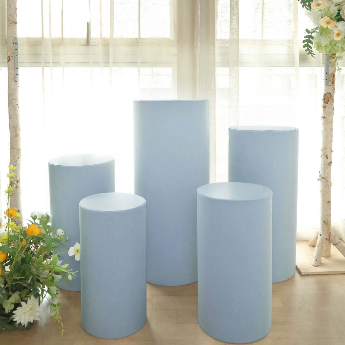 Blue display pedestals arranged in a bright, airy space with flowers.