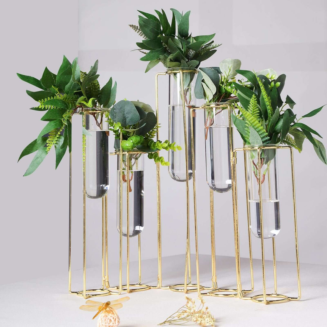 Gold plant stand with test tube vases and greenery arrangement.