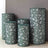 Decorative cylindrical storage bins with green leaf patterns.