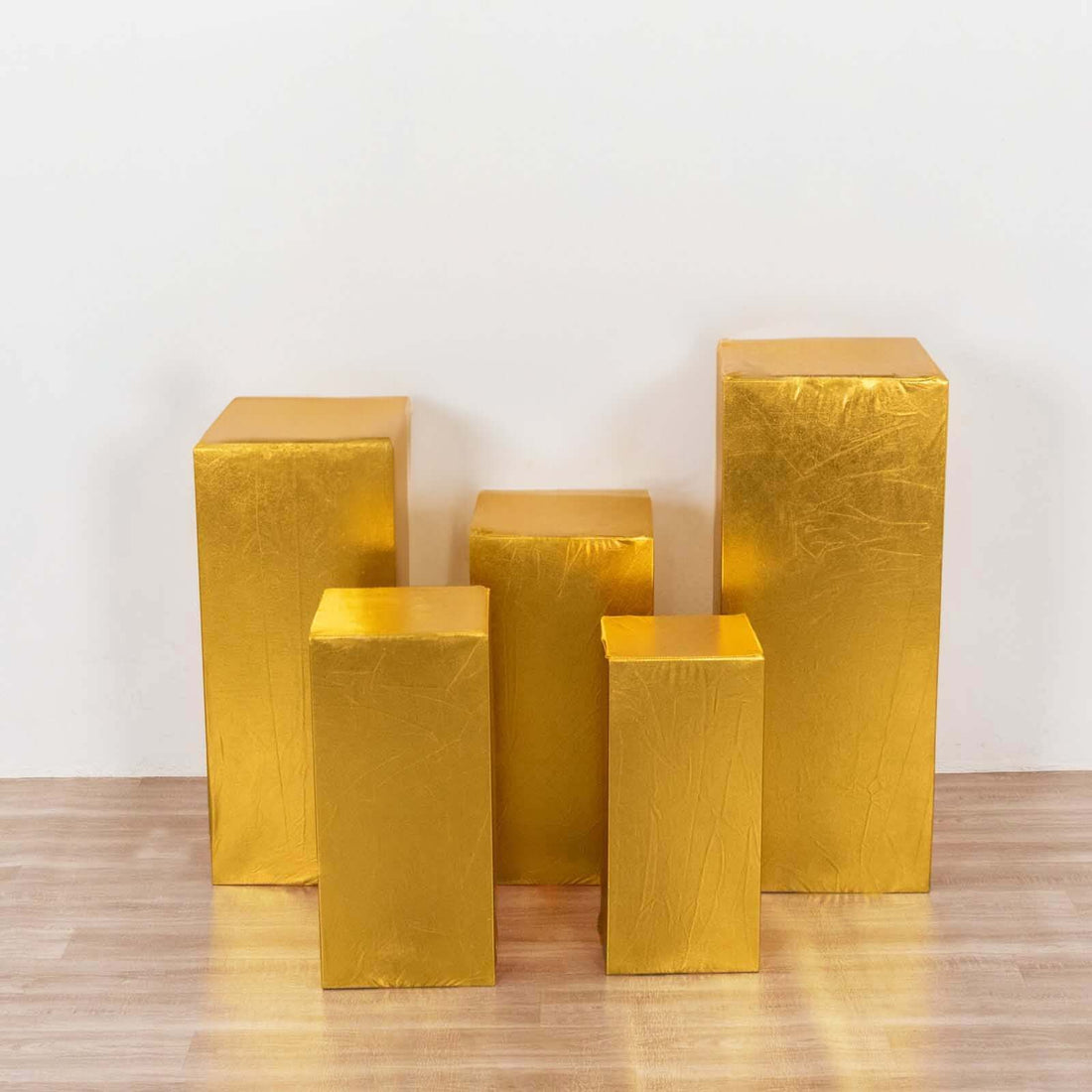 Gold display pedestals in various heights on a wooden floor