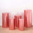 Set of five pink metallic pedestals in various heights on a light background.
