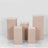 Set of five pink display pedestals in various heights on a plain backdrop.