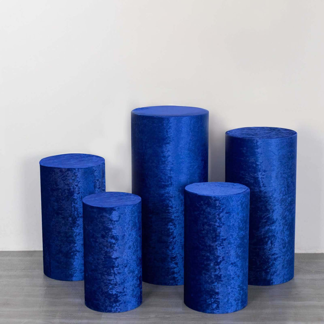 Set of five blue velvet display pedestals in various heights.