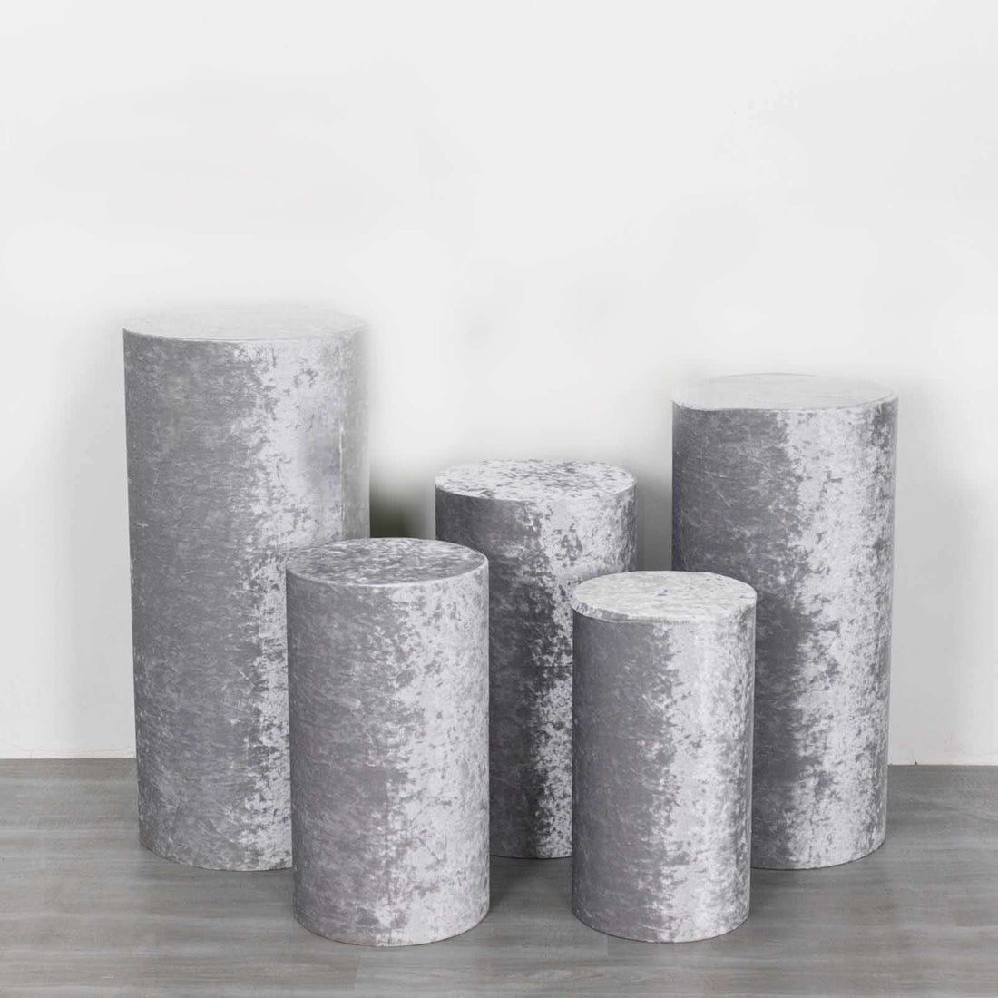 Set of five decorative gray pedestals in various heights and shapes.