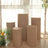 Five beige cylindrical pedestals arranged with flowers in a well-lit room.
