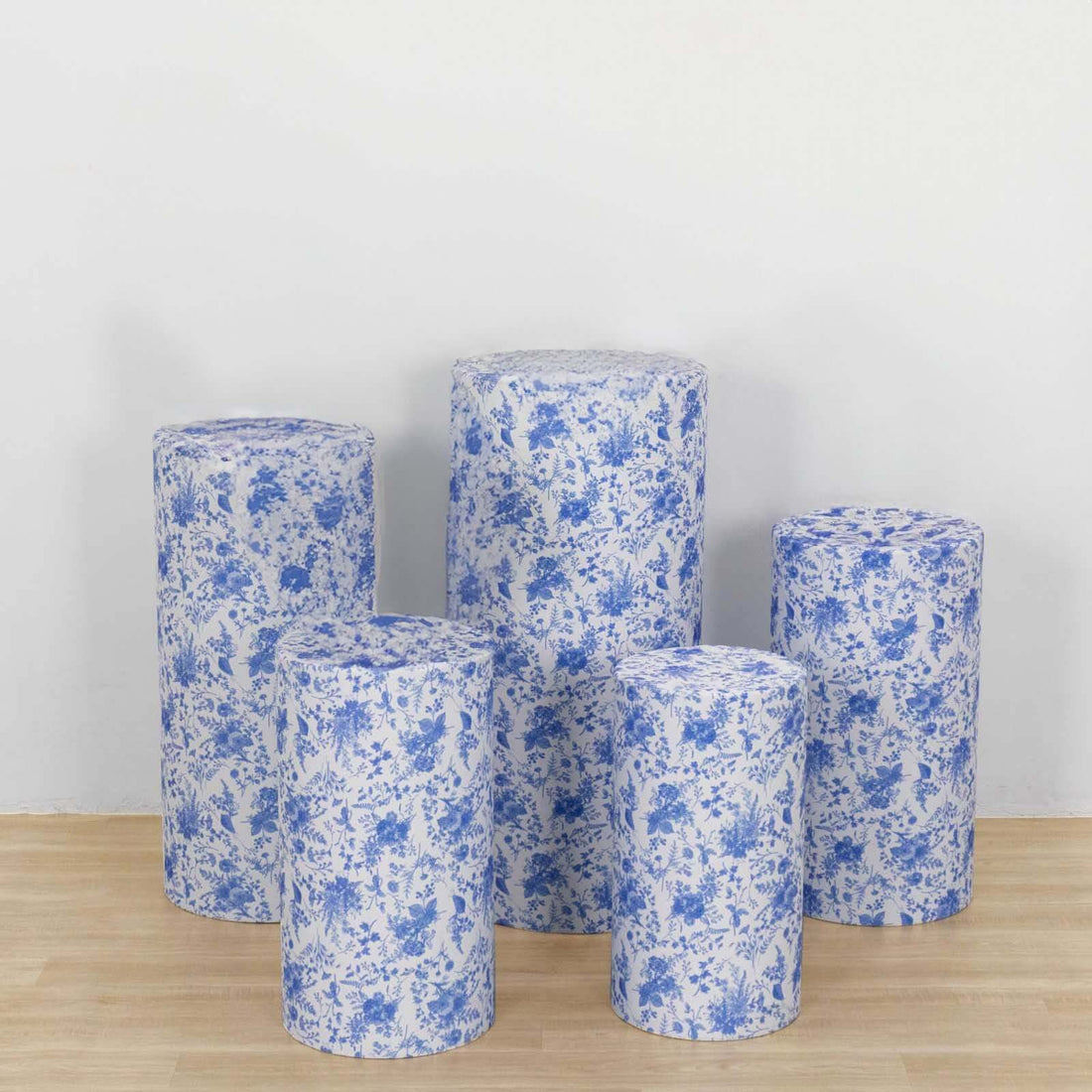 Set of five blue floral-patterned cylindrical stools on a light wooden floor.