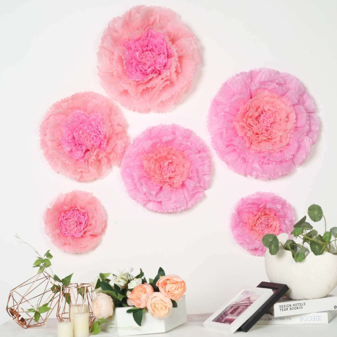 Pink paper flower wall decor in various sizes on a white background.