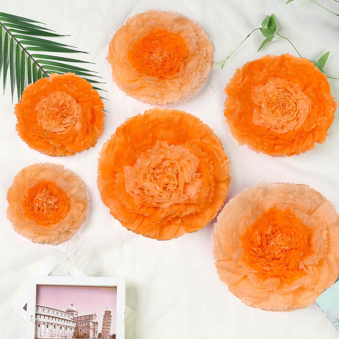 Orange paper flower decorations in various sizes on a white background.