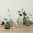 Vintage green glass vases with flowers on a wooden table.