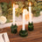 Green glass candle holders with white candles, elegantly displayed on a wooden table.