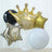 Gold crown and star-shaped balloons in various colors for celebration decor.