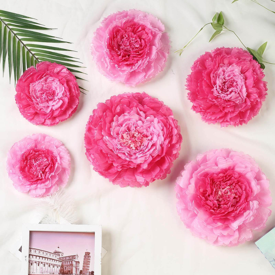Pink paper flower decorations in various sizes arranged on a white background.