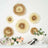 Decorative paper flowers in soft beige and cream hues on a wall with a floral arrangement.
