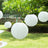 Hanging white paper lanterns in a garden setting.