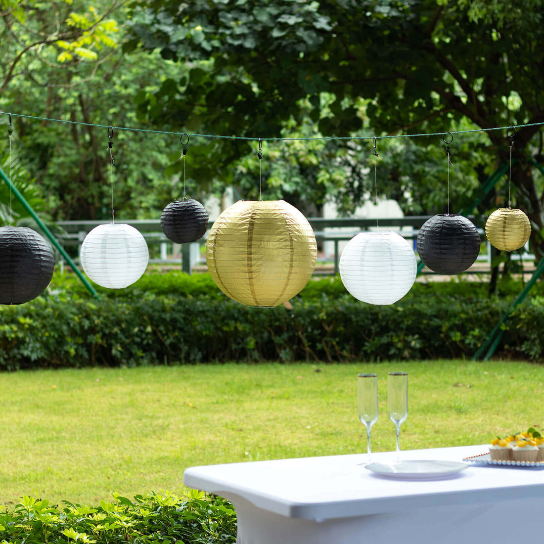 Decorative hanging lanterns in black, white, and gold for outdoor celebrations.