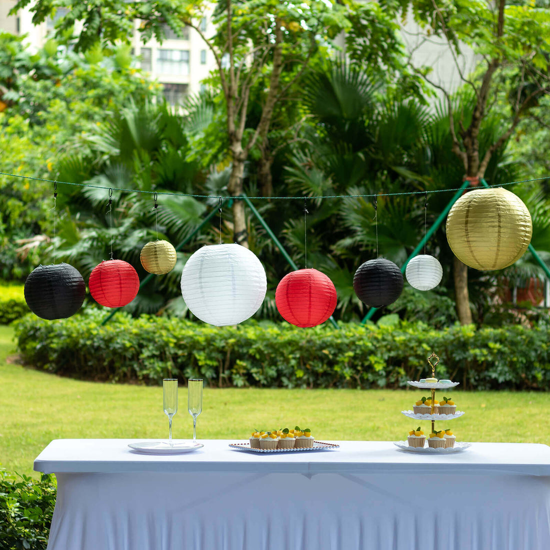 Decorative paper lanterns in red, black, gold, and white at an outdoor party setting.