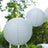 White paper lanterns hanging outdoors in a garden setting.