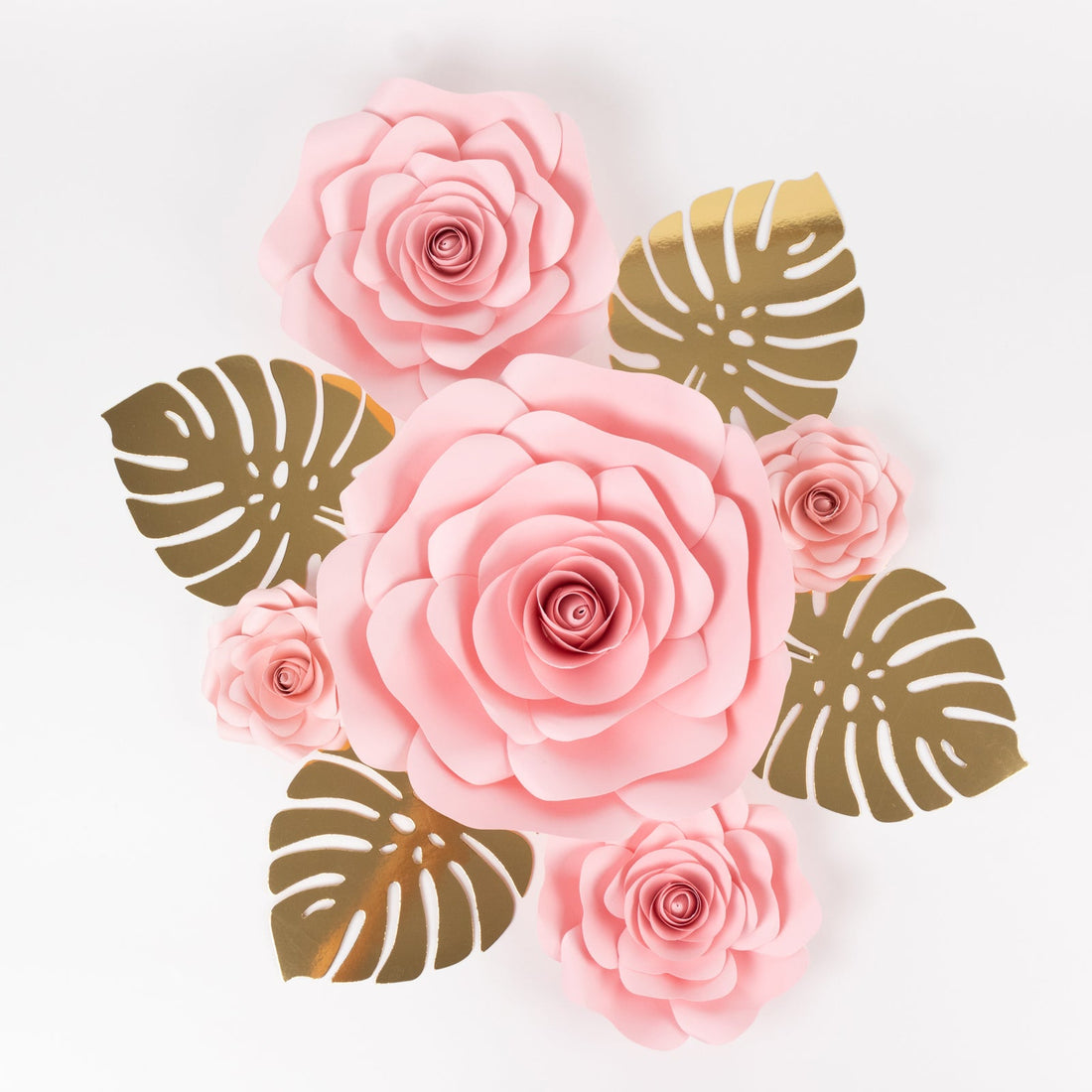 Pink paper roses with gold leaves on a plain background