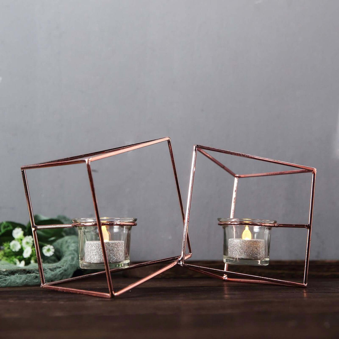 Rose gold geometric candle holders with glass cups.