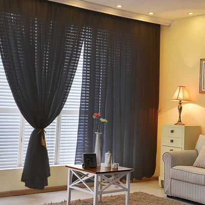 Black sheer curtains draping a window in a cozy living room setting.