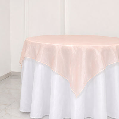 Sheer blush pink round tablecloth over white table skirt in minimalist room