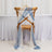 Wooden cross-back chair draped with blue and white sheer fabric.