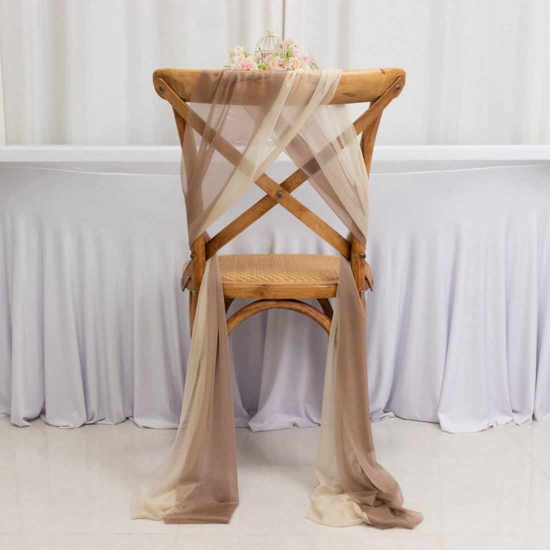 Wooden chair draped with sheer fabric in soft brown and beige tones.