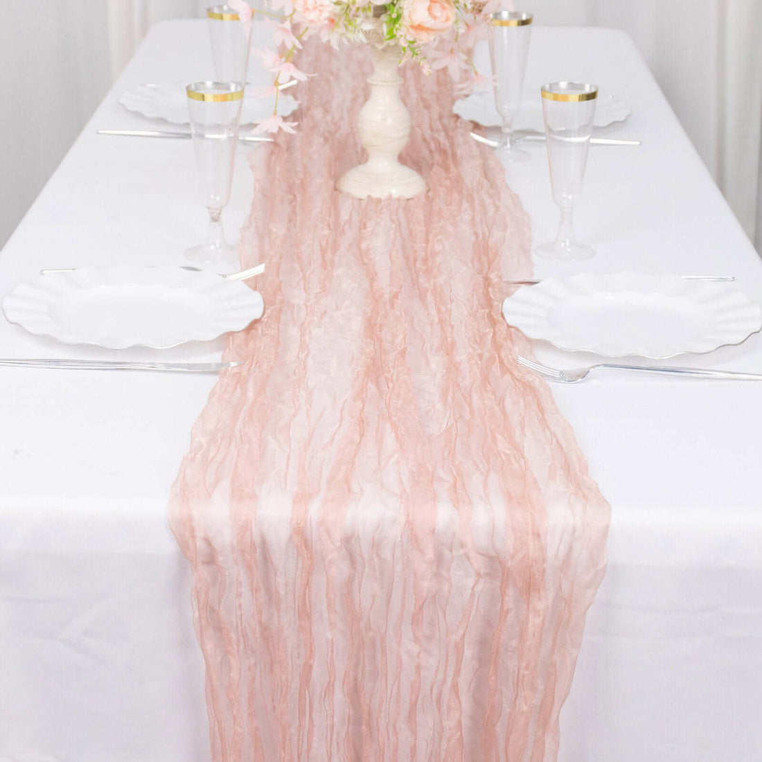 Pink textured table runner on a white table setting with elegant dinnerware.
