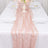 Pink textured table runner on a white table setting with elegant dinnerware.