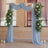 Wedding arch with blue drapes and floral arrangements in a decorated venue.