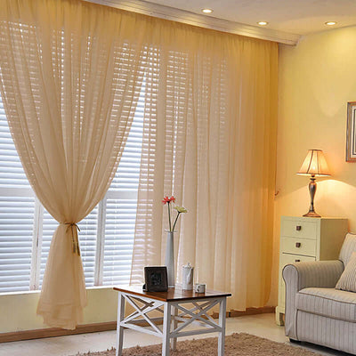 Sheer yellow curtains hanging in a cozy living room setting.