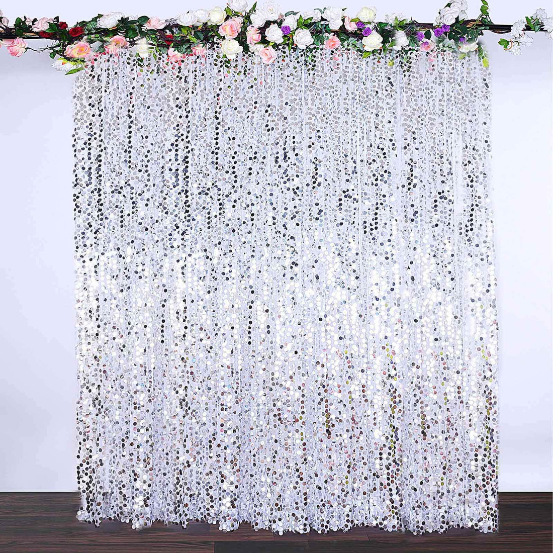 White sequin curtain draped with floral accents for event decoration.