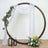 Wooden circle arch with draped fabric and floral accents for events.