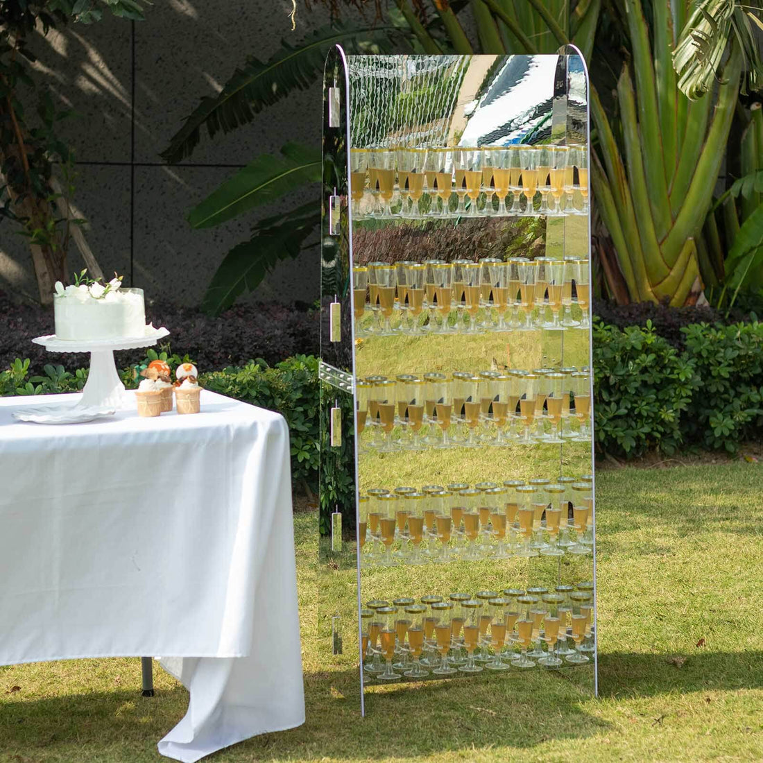 Stylish mirrored champagne display with glasses at an outdoor event setting.