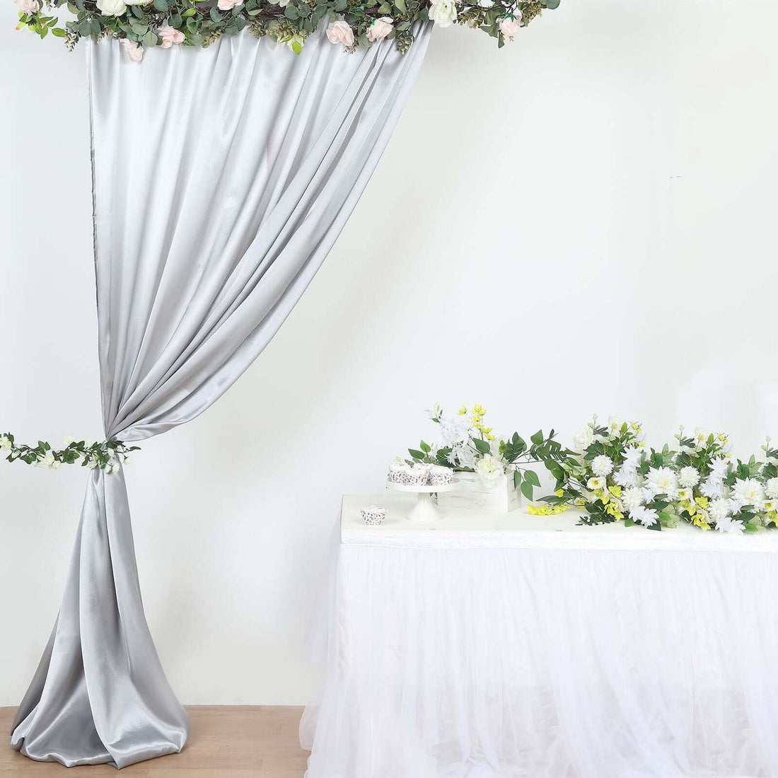 Elegant wedding decoration with draped silver fabric and floral arrangements.