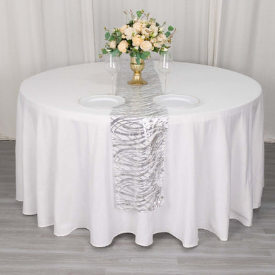 Elegant round table set with floral centerpiece and silver runner.