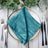 Teal satin table napkin elegantly arranged on a decorative plate. #whtbkgd