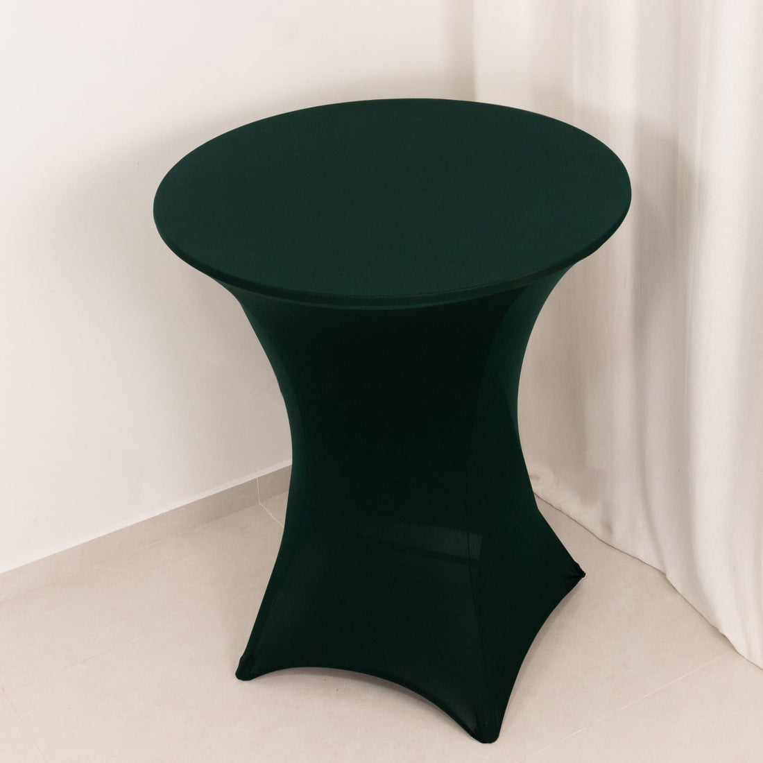 Green stretch table cover on a round table in a minimalist setting.