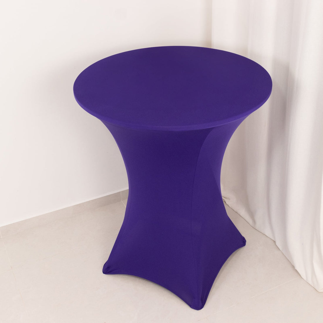 Purple stretch table cover on a round table against a plain background.