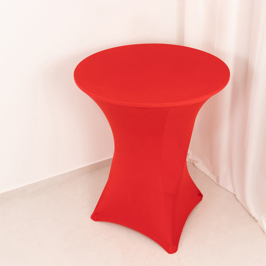 Red stretch table cover on a round table against a white backdrop.