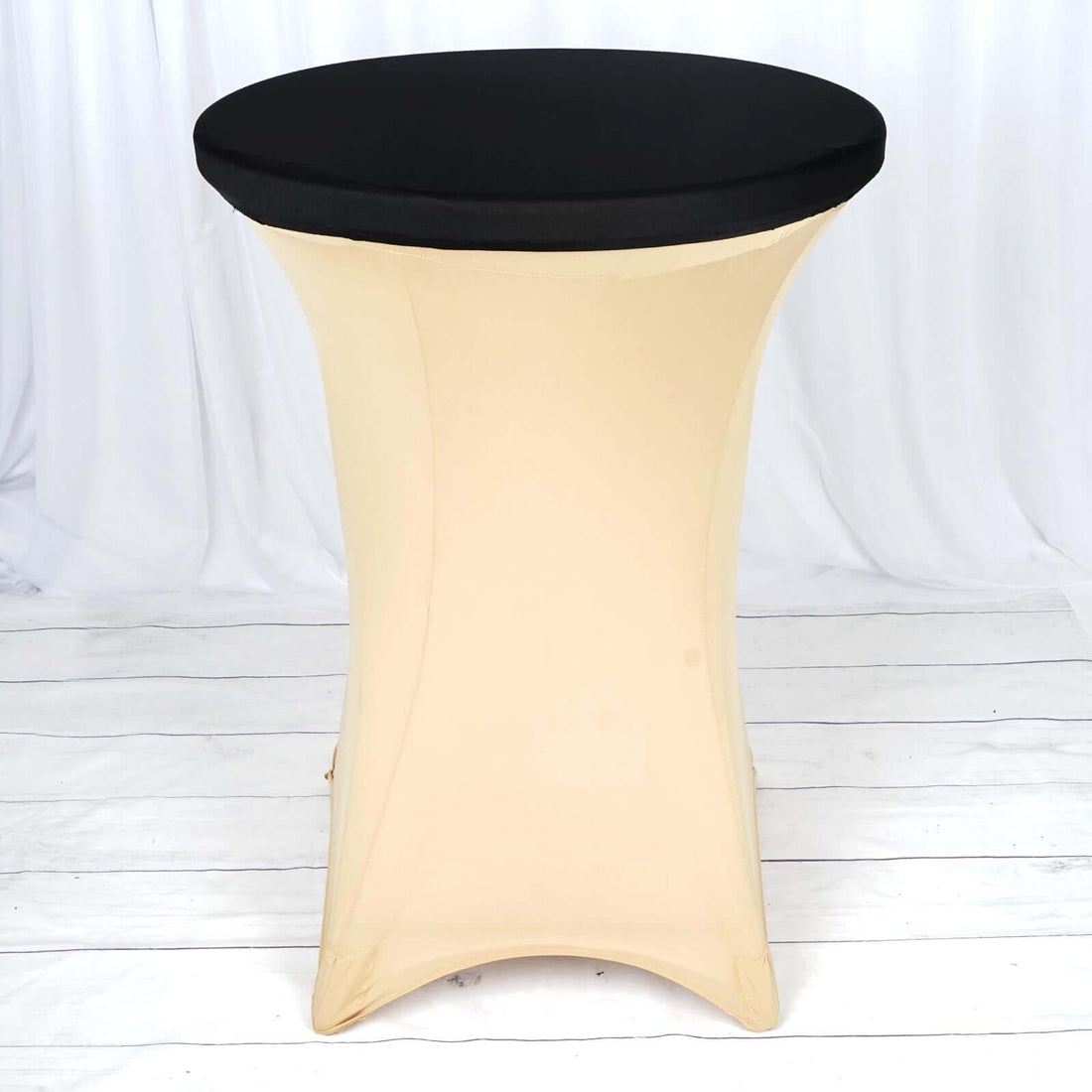 Black round table with a beige stretch cover on a white backdrop